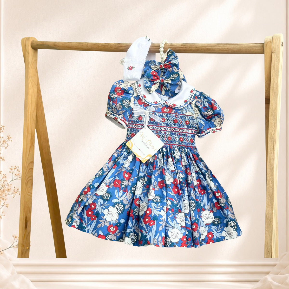 Blue floral hand-smocked girls dress with embroidered collar and matching accessories